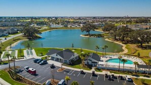 A residential area with a large lake, a parking lot, and a building with a modern design. - Into The Mystic - 3/2 Dog Friendly w/ Golf Cart in The Villages (St Catherine, The Villages)