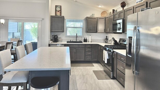 A modern kitchen with dark cabinets, stainless steel appliances, and a large island with seating. - Into The Mystic - 3/2 Dog Friendly w/ Golf Cart in The Villages (St Catherine, The Villages)