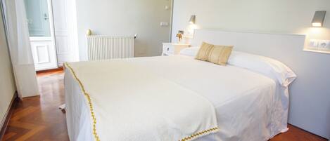 A hotel room with a large bed, a nightstand, a wall-mounted lamp, and a painting of a beach scene.