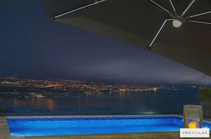 Vista nocturna d'una piscina amb un paisatge urbà al fons.