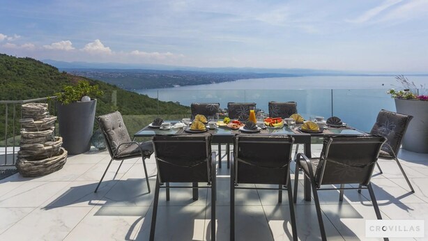 A dining table set for four with a scenic view of a body of water and hills. - Villa Diamond in Opatija - Crovillas (Opatija)