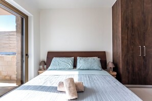 A bedroom with a bed, two pillows, a nightstand with a lamp, and a wardrobe. - Elpida Luxury Villa, Private Pool, Fantastic View (Chania)