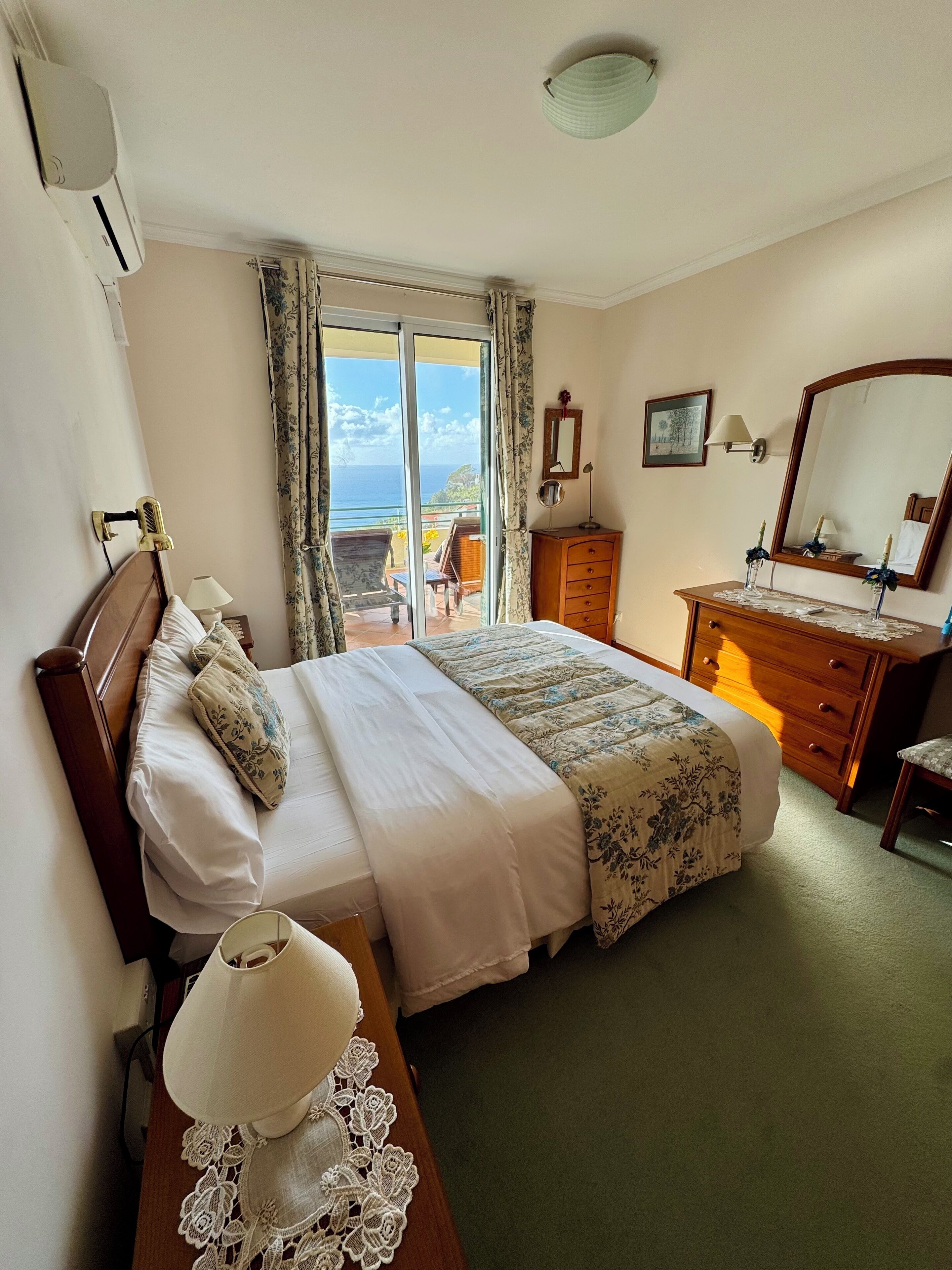 Une chambre d’hôtel avec un lit, une commode, un miroir et une vue sur l’océan.