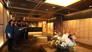 Een hotel lobby met een receptiebalie, een rij kastjes en een bloemstuk.