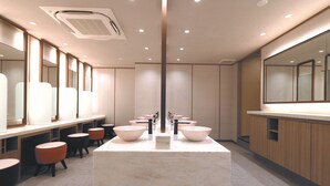 Een moderne badkamer met een centraal geplaatst marmeren wastafel, meerdere spiegels en houten kastjes.