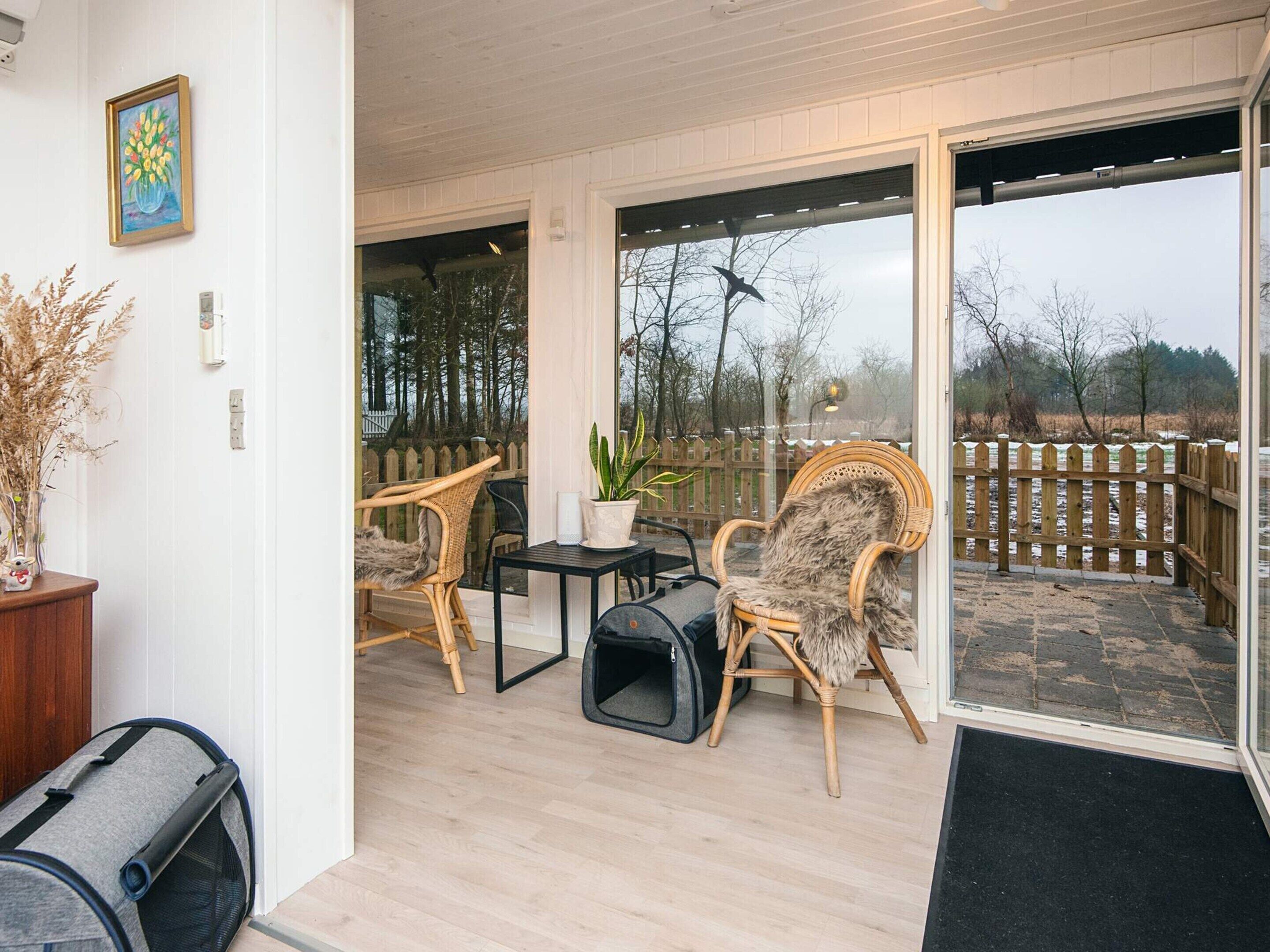 En hyggelig patio med fletstole, et lille bord og en hundeseng.