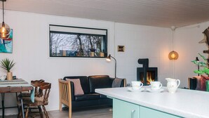 Ein gemütlicher Wohnbereich mit einer Couch, einem Esstisch mit Stühlen, einer Kücheninsel und einem Kamin.