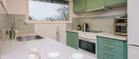 A modern kitchen with a stainless steel sink, a stove, and a built-in oven.