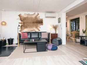 A modern living room with a large fur rug, a leather sofa, a coffee table, and a view of the outdoors. - 4 Star Holiday Home in Bording (Bording)