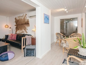 A modern living room with a leather sofa, a large fur rug, wicker chairs, and a potted plant. - 4 Star Holiday Home in Bording (Bording)
