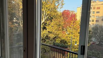 Ein Balkon mit Blick auf Herbstbäume und ein Gebäude im Hintergrund.