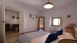 Ein Schlafzimmer mit einem Bett, einem Sessel, einem Schreibtisch und einem Fenster.