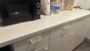 Eine Küche mit einer Mikrowelle, Schränken und verschiedenen Küchenutensilien auf der Arbeitsfläche.