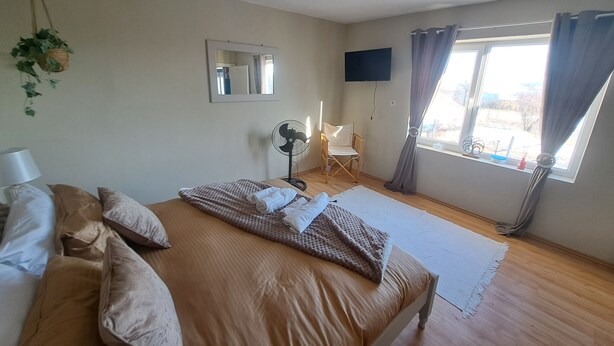 A bedroom with a bed, a chair, a TV, and a window with curtains. - Boutique Farm Stay: Friendly Dogs & Family-Friendly Farm Meals. Optional Extras. (Kovachevets)