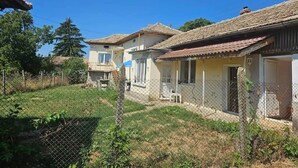 Una hilera de casas con techo de tejas de arcilla, un patio cubierto de césped y una cerca de malla metálica.