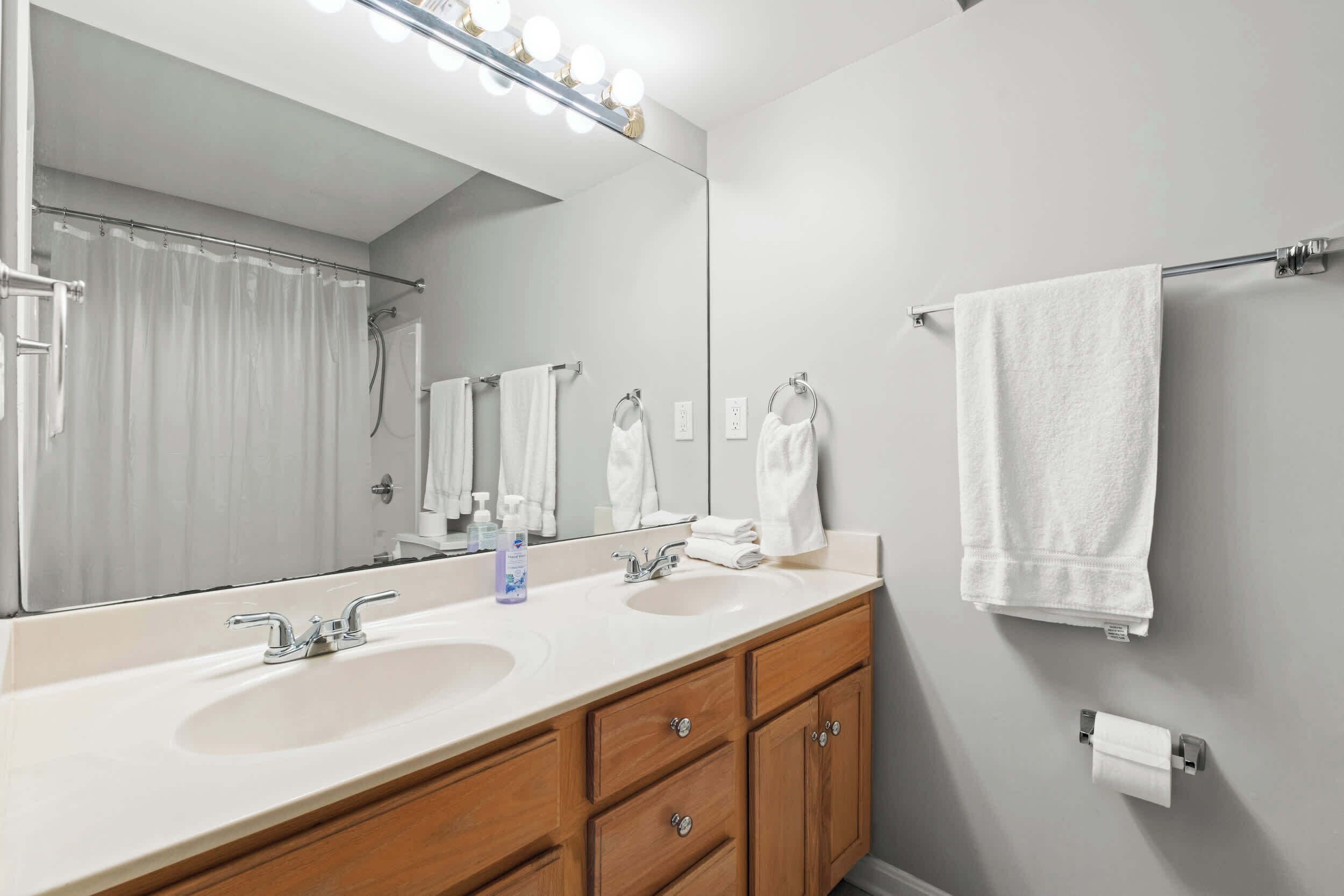 A bathroom with a double sink vanity, a large mirror, and a towel rack.