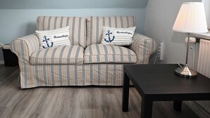 A striped sofa with two pillows, a black table, and a lamp. - The Lodge II - with private garden and beach chair (Büsum)