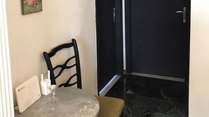 Un pequeño comedor con una mesa redonda, una sola silla y un menú colgado en la pared.