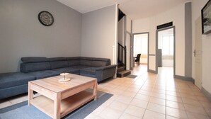 Una sala de estar moderna con un sofá seccional, una mesa de centro de madera y un reloj de pared.