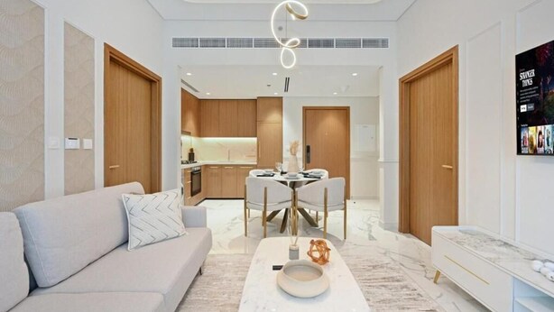 A modern living room with a sofa, a coffee table, and a dining area with a table and chairs. - 221Bloomfields Grandr2BRAzizi Riviera 67 (Dubai)