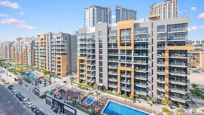 A modern residential building with multiple floors, balconies, and a swimming pool. - 221Bloomfields Grandr2BRAzizi Riviera 67 (Dubai)
