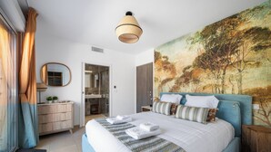 Ein Schlafzimmer mit einem großen Bett, einem Gemälde an der Wand, einer Holzkommode und einem Spiegel.