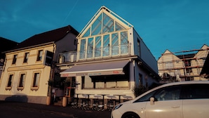 A building with a glass front, outdoor seating, and a Coca-Cola sign. - Hotel am Hafen Leverkusen (Leverkusen)