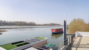 A river view with a red boat docked, a grassy rooftop, and a clear sky. - Hotel am Hafen Leverkusen (Leverkusen)
