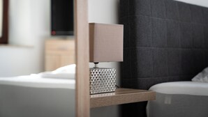A neatly arranged hotel room with a bed, a bedside table with a lamp, and a television on a stand. - Hotel am Hafen Leverkusen (Leverkusen)
