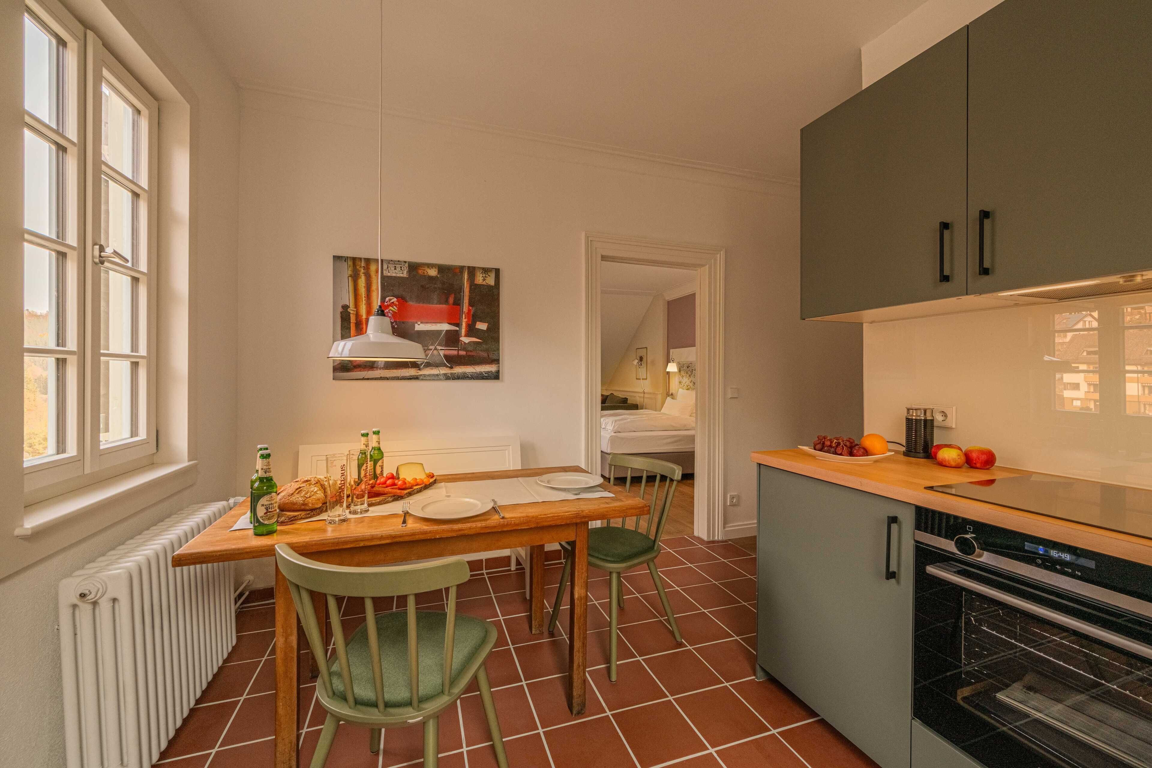 A compact kitchen with a dining table, chairs, and a built-in oven.