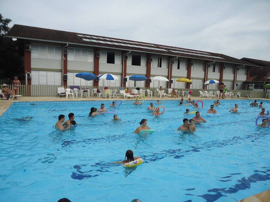A swimming pool with people and lounge chairs.