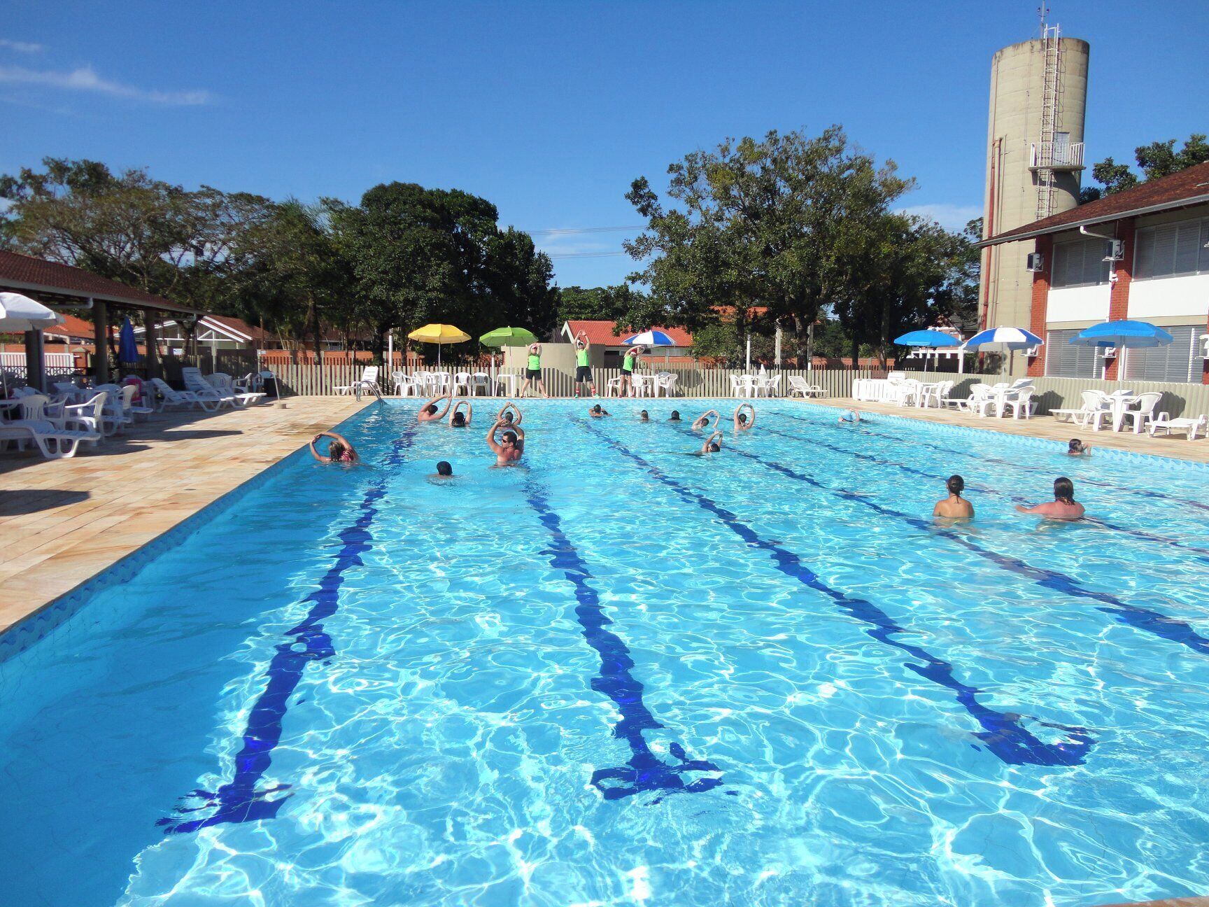 A swimming pool with multiple lanes, surrounded by lounge chairs and umbrellas.