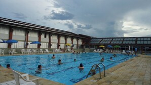 Un espace piscine doté de plusieurs couloirs, entouré de chaises longues et de parasols.