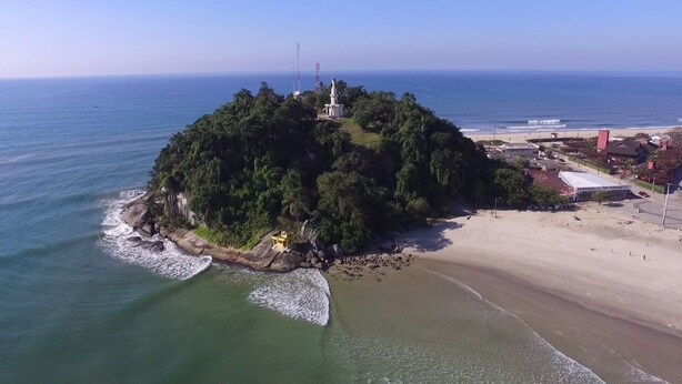 Vue aérienne d’une petite île avec un phare, entourée d’une plage et de l’océan.