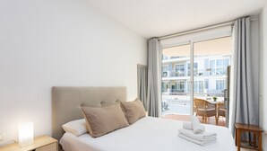 Een hotelkamer met een bed, een nachtkastje, een tafel met stoelen en uitzicht op het gebouw.