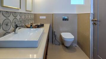 Un baño moderno con un lavamanos grande, un inodoro y una zona de ducha.