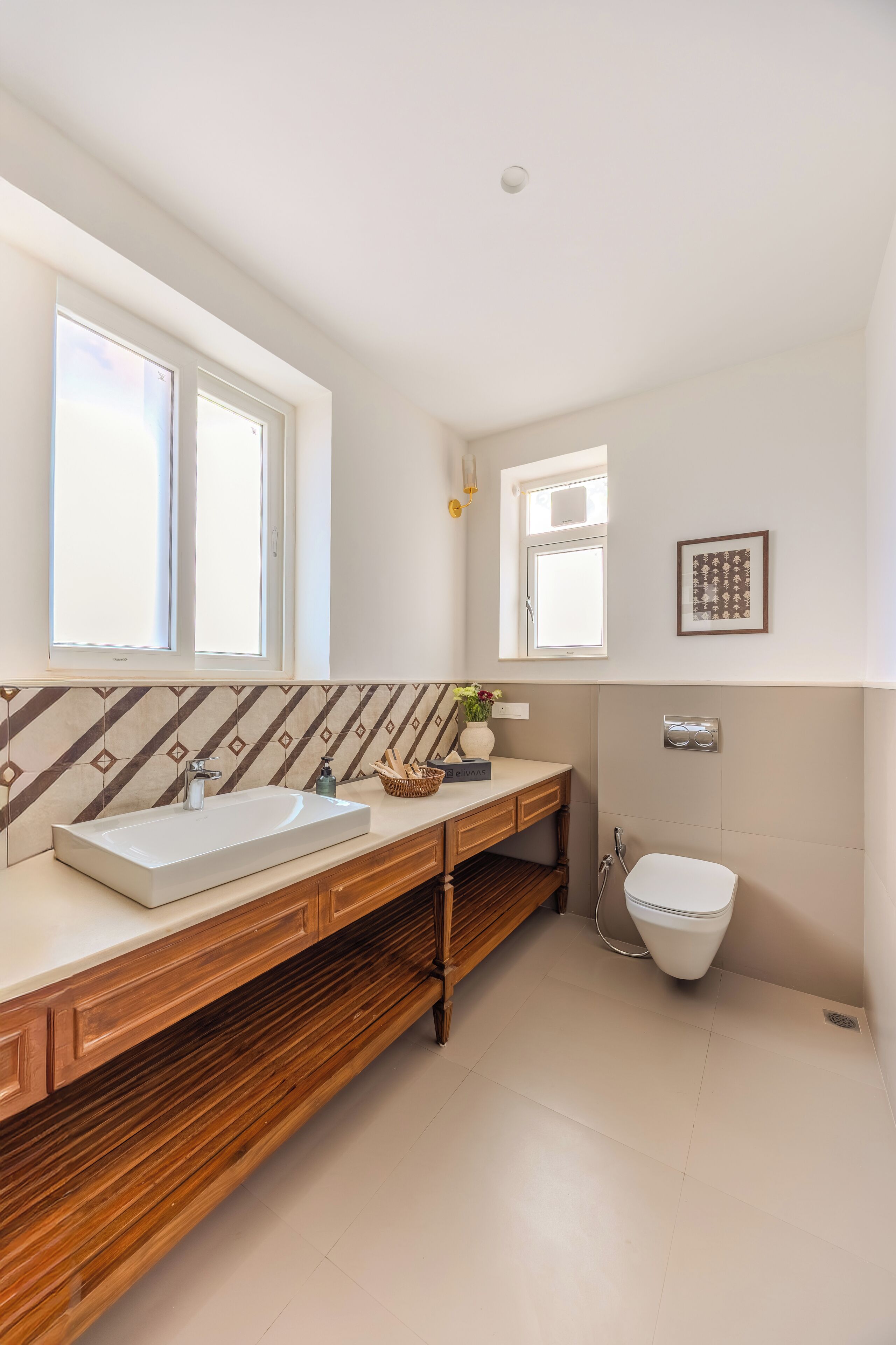 A modern bathroom with a wooden vanity, a large window, and a toilet.