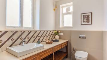 A modern bathroom with a wooden vanity, a large window, and a toilet.