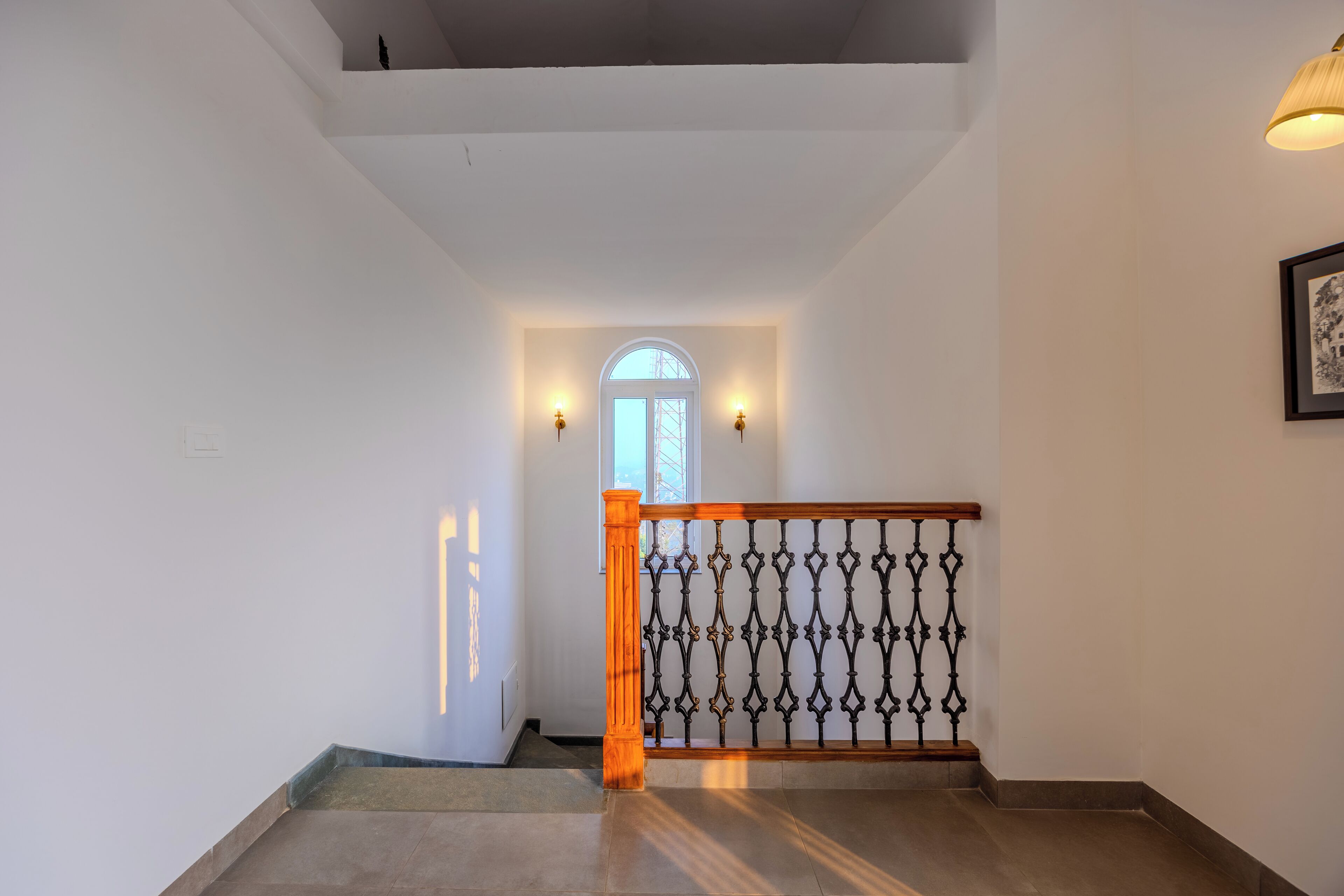 Un escalier doté d’une main courante en bois et d’une balustrade en métal, menant à une porte avec un panneau de verre et un cadre blanc.