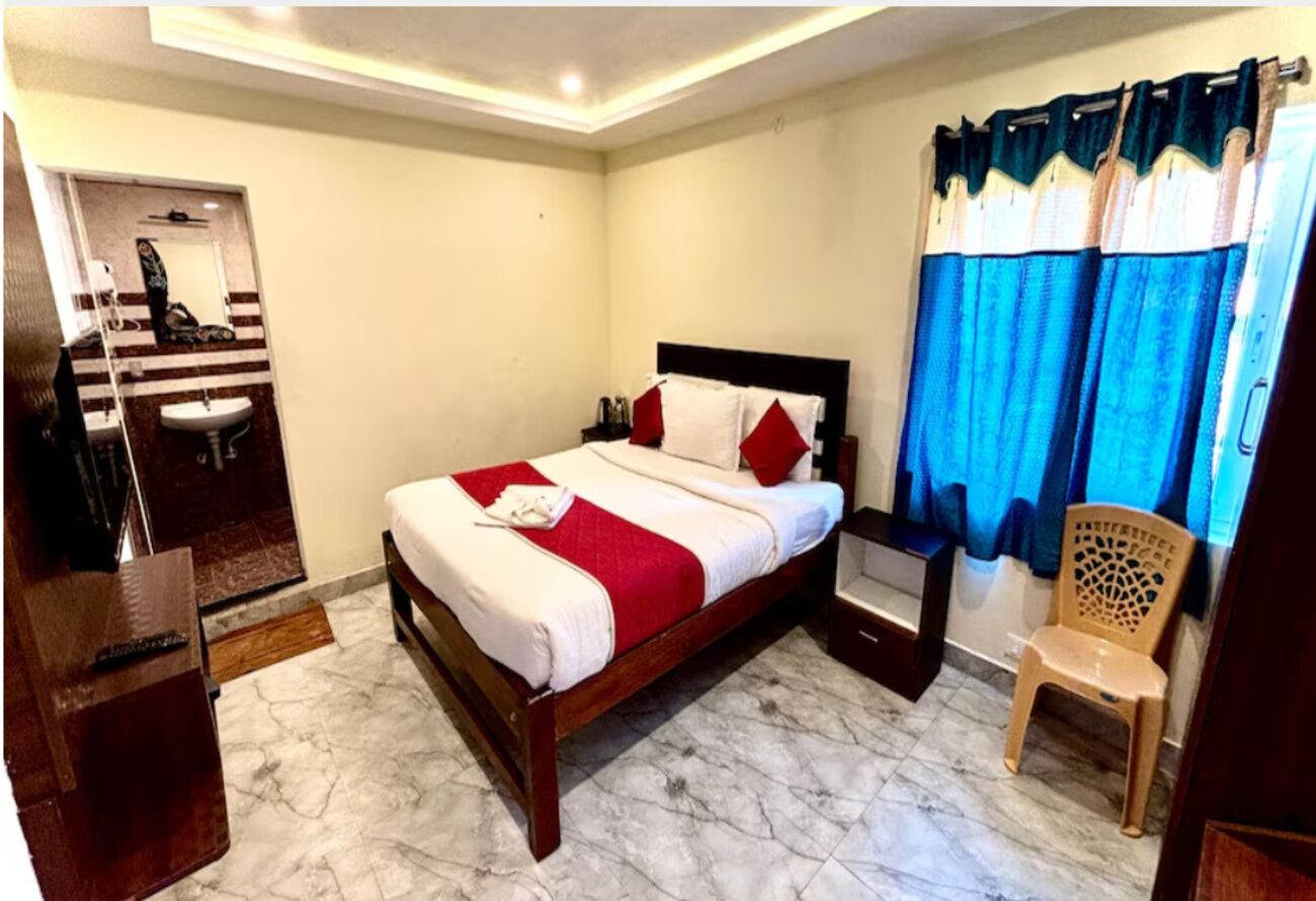Une chambre à coucher comprenant un lit, une chaise, une table de chevet et un miroir, ainsi qu’une salle de bain avec un lavabo et un miroir.