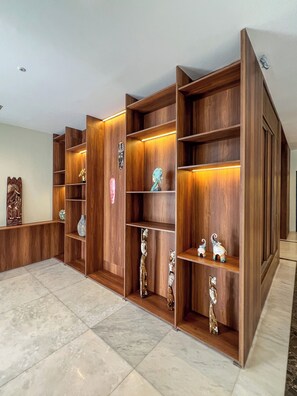 A spacious room with a large wooden bookshelf filled with decorative items. - Snug Studio Haven (Accra)