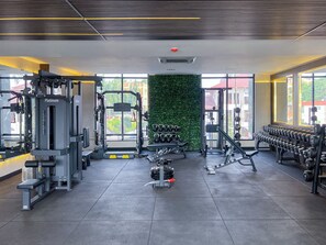 A modern gym with various exercise equipment, a green wall, and large windows. - Snug Studio Haven (Accra)