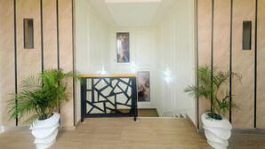A hallway with a geometric decorative screen, potted plants, and a framed artwork on the wall. - LinQues & Bethel Residences (Ibadan)