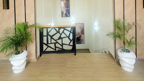 A modern hallway with a geometric black railing, potted plants, and a framed artwork on the wall. - LinQues & Bethel Residences (Ibadan)