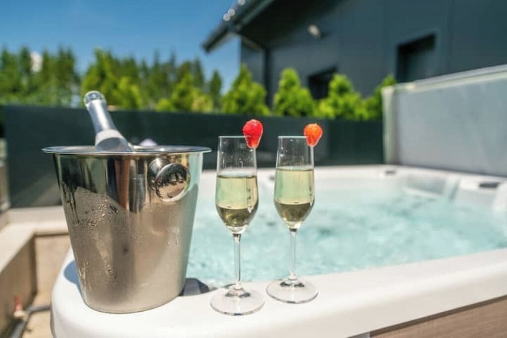 A hot tub with two glasses of champagne and a bucket of ice.