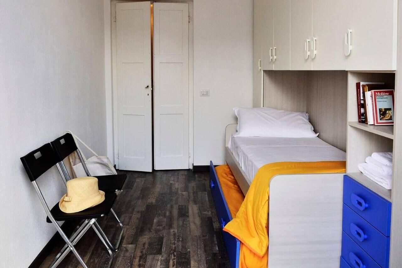 A compact room with a bed, a chair, a wardrobe, and a door.