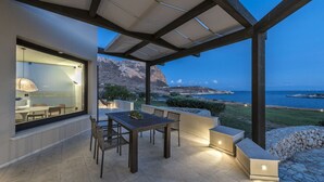 Un patio al aire libre con una mesa y sillas, una pérgola y vistas al mar y a las montañas.