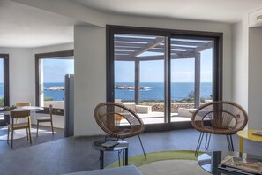 A modern room with large windows, wicker chairs, a round table, and a view of the sea. - Villa Stornella by MMega (Favignana)
