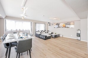 A modern living space with a dining area, sofa, and a large mirror. - Luxury 3BR,2-shower,3-toilet!Theater,full kitchen,kids' room& garage.Family-f... (Midori Sumidaku)