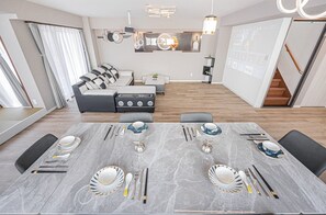 A modern dining area with a marble table set for six, a sofa, and a staircase. - Luxury 3BR,2-shower,3-toilet!Theater,full kitchen,kids' room& garage.Family-f... (Midori Sumidaku)